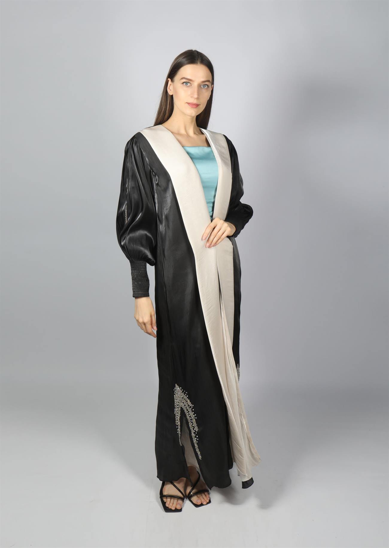 Model wearing a black and ivory abaya in a studio setting